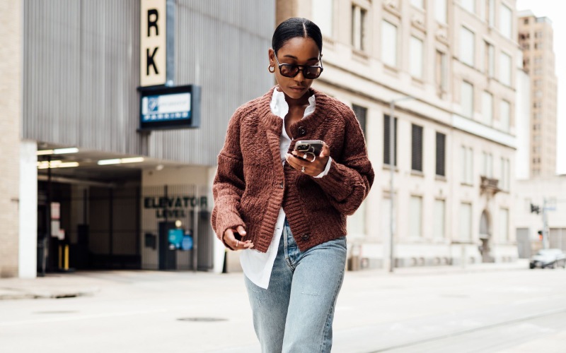 a woman walking down a sidewalk with a phone