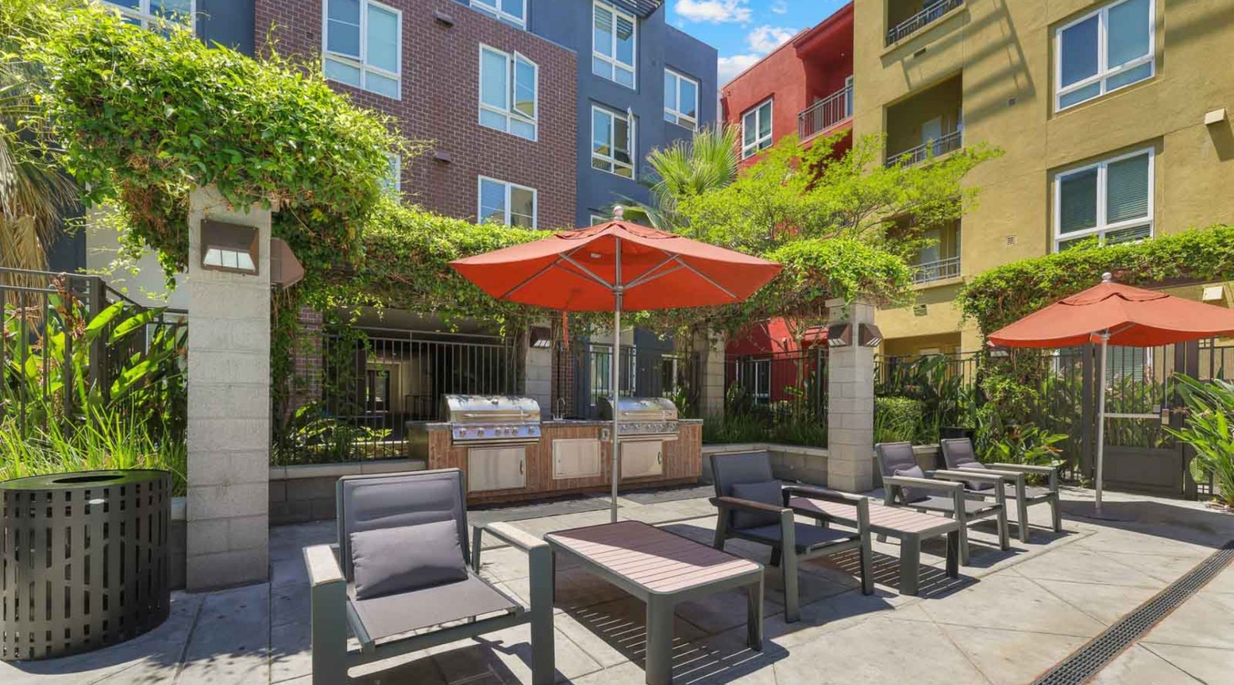 an outdoor courtyard with a grilling area and tables with umbrellas